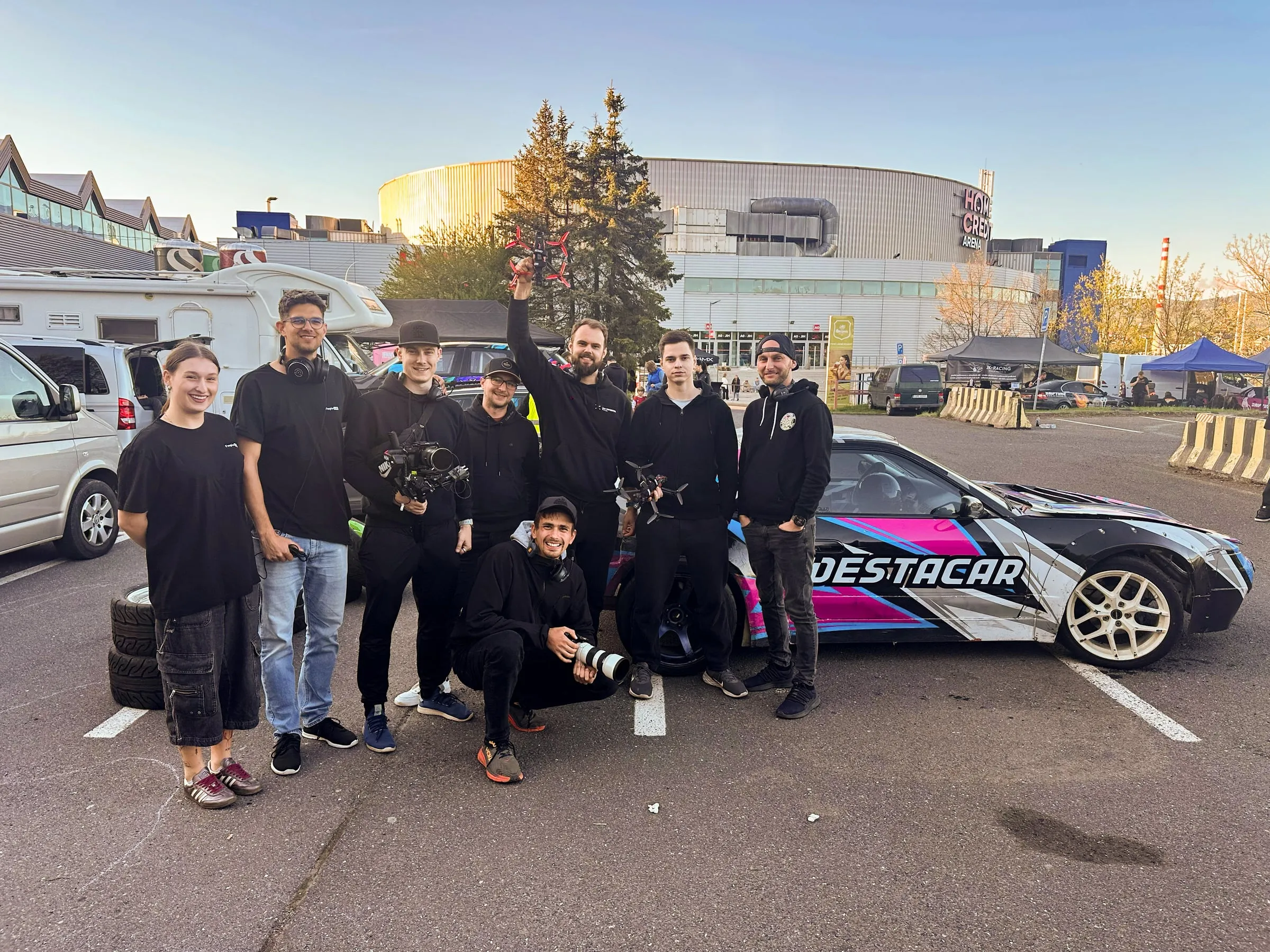 Devět členů týmu Forpix Live s kamerami u driftového vozu na parkovišti