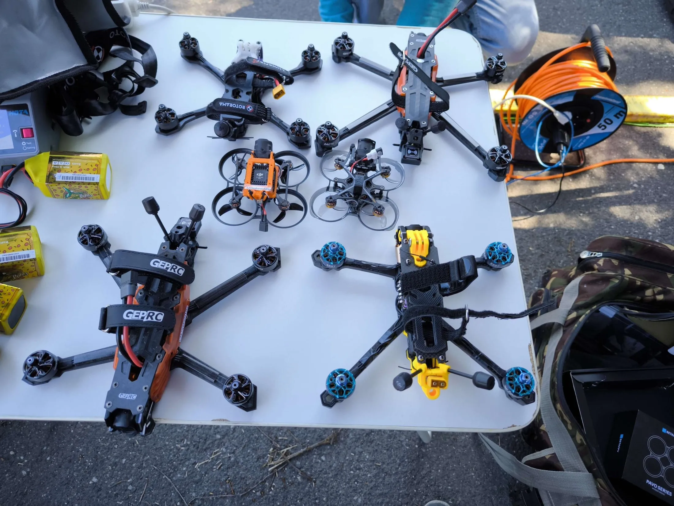 Šest FPV dronů a nabité baterie připravené před závodem