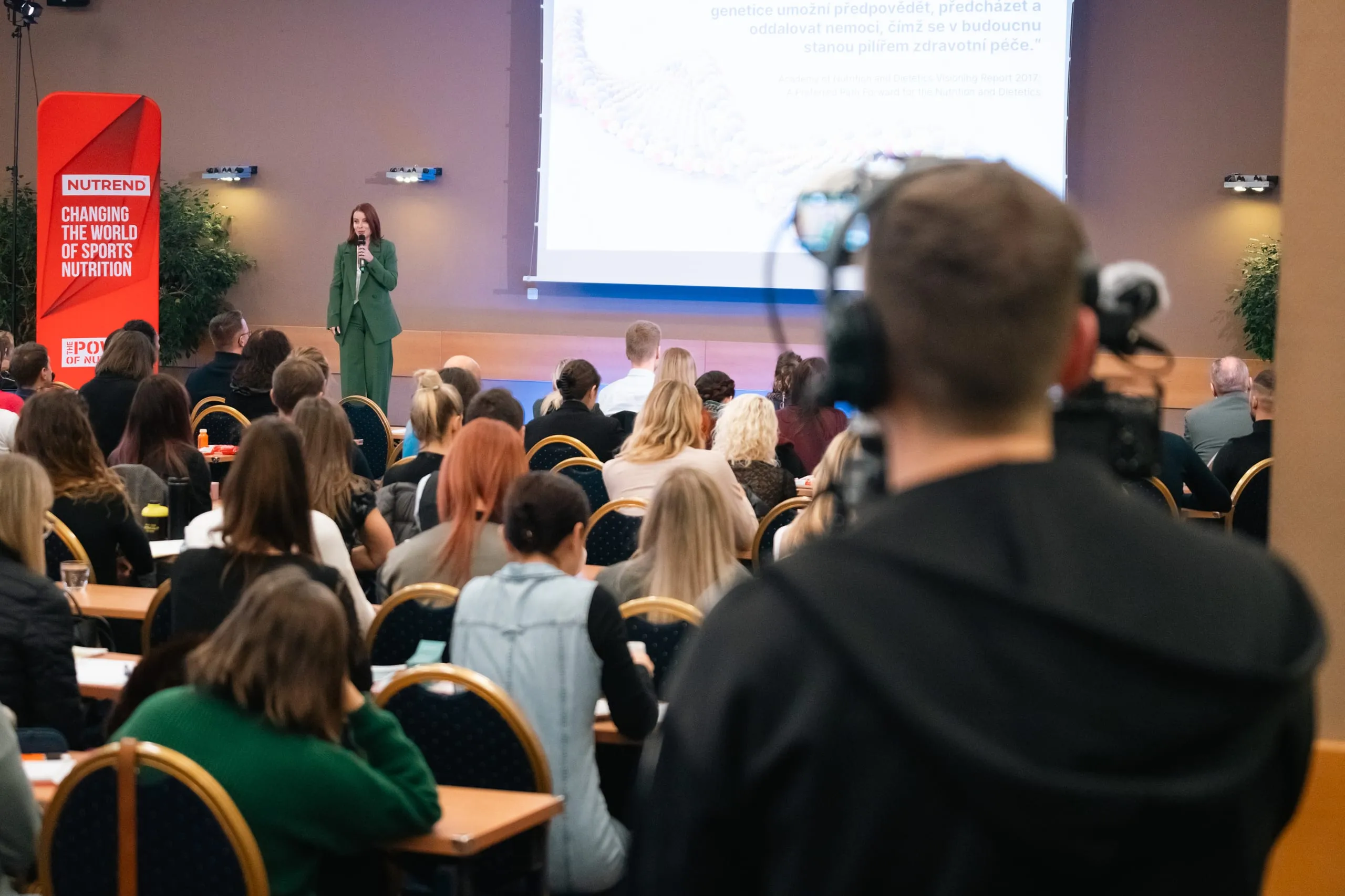 A speaker addressing a packed conference room, a Forpix Live camera operator in the foreground