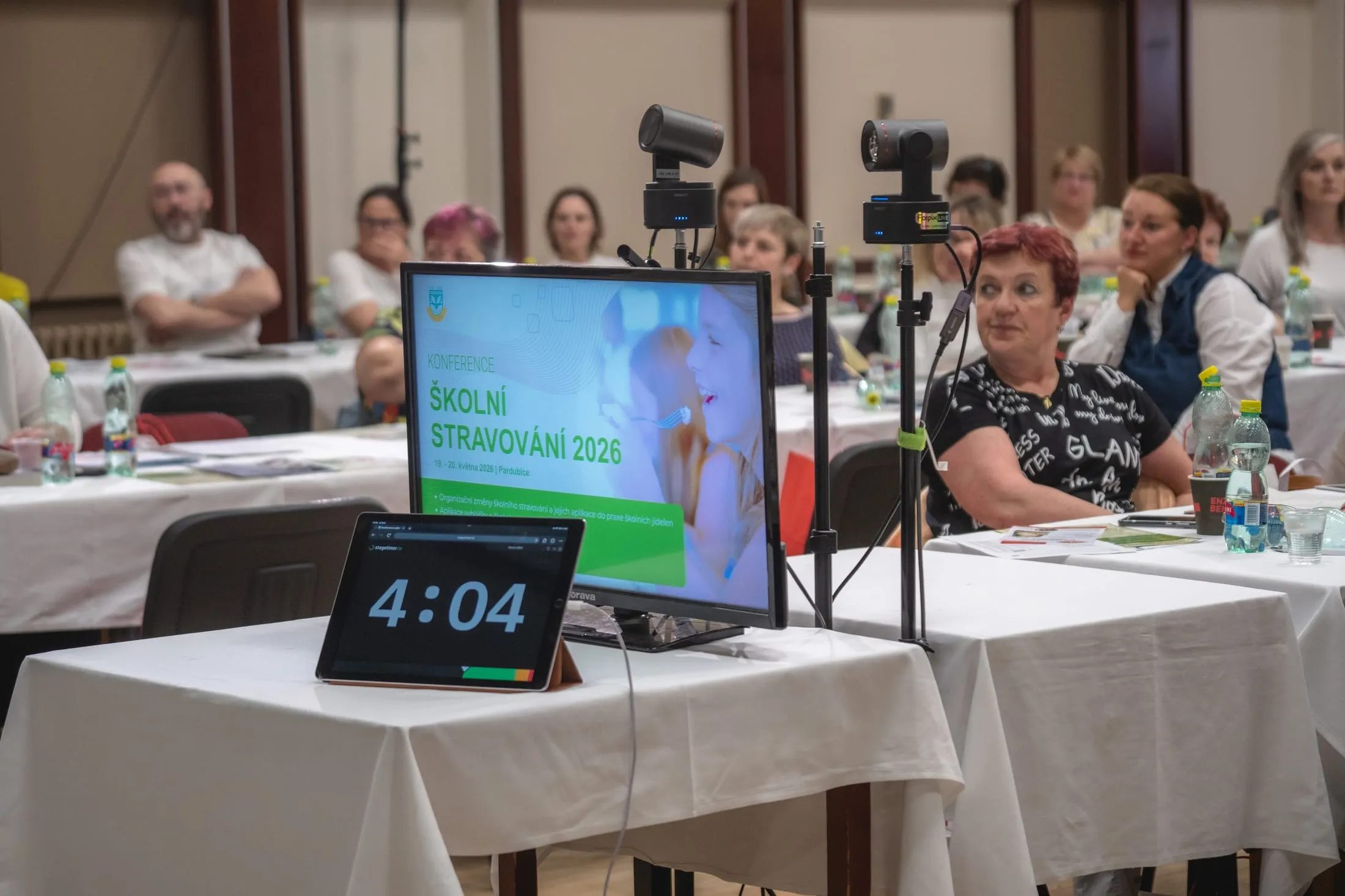 Odpočet pro řečníka, kontrolní monitor a dvě kamery mezi stoly